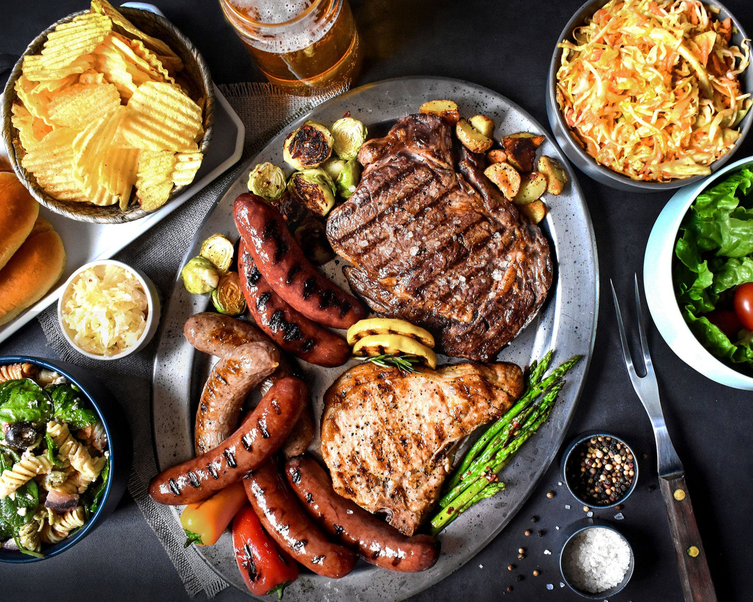 backyard barbeque on a silver platter with various sides served with it