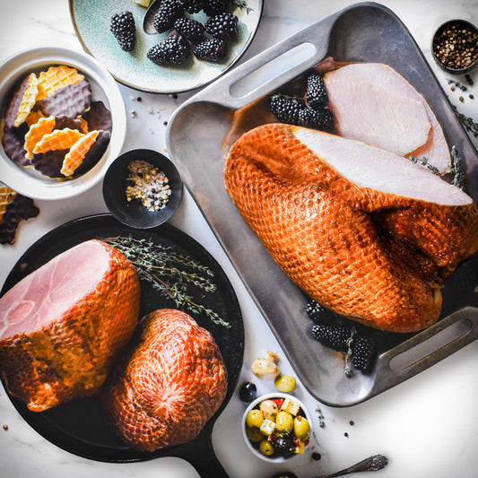 bone-in ham and turkey duo on serving trays with blackberry garnish