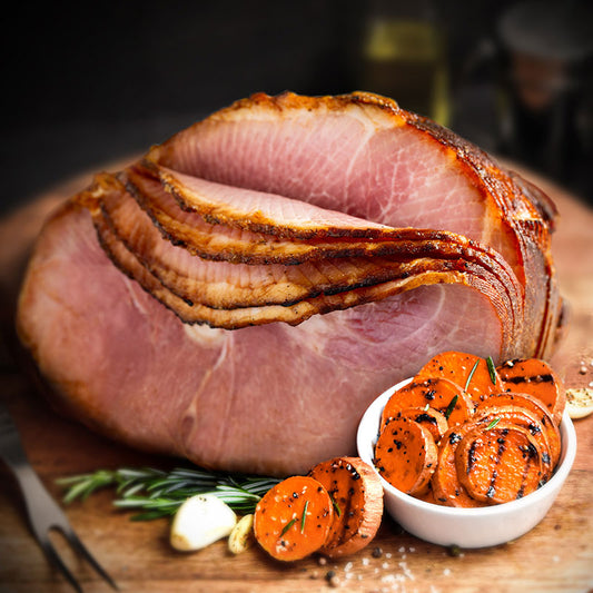 bone-in spiral sliced ham on a wooden serving tray with sweet potatoes in front