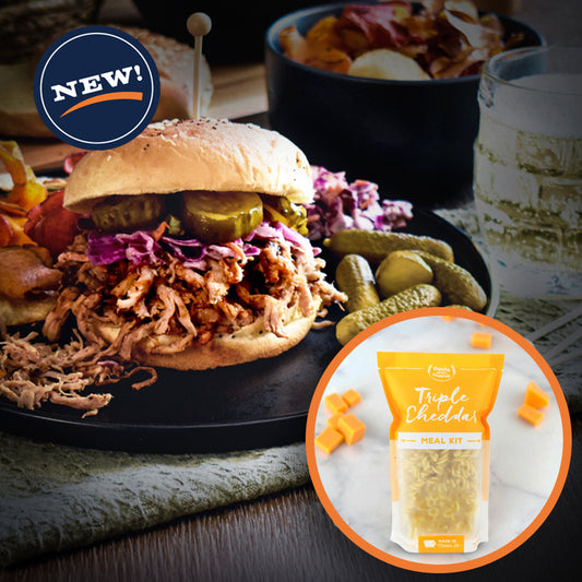 Shredded pork sandwich with pickles and slaw on a black plate. Inset with Pasta of the Prairie Triple Cheddar Meal Kit.