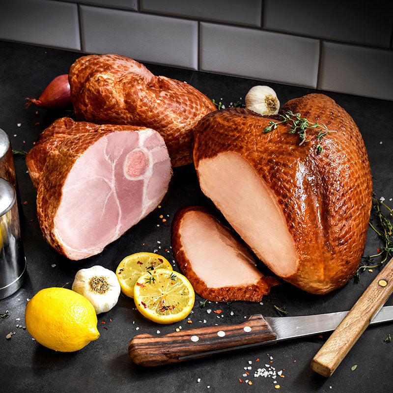 bone-in ham turkey duo on a black countertop with lemons in front of it