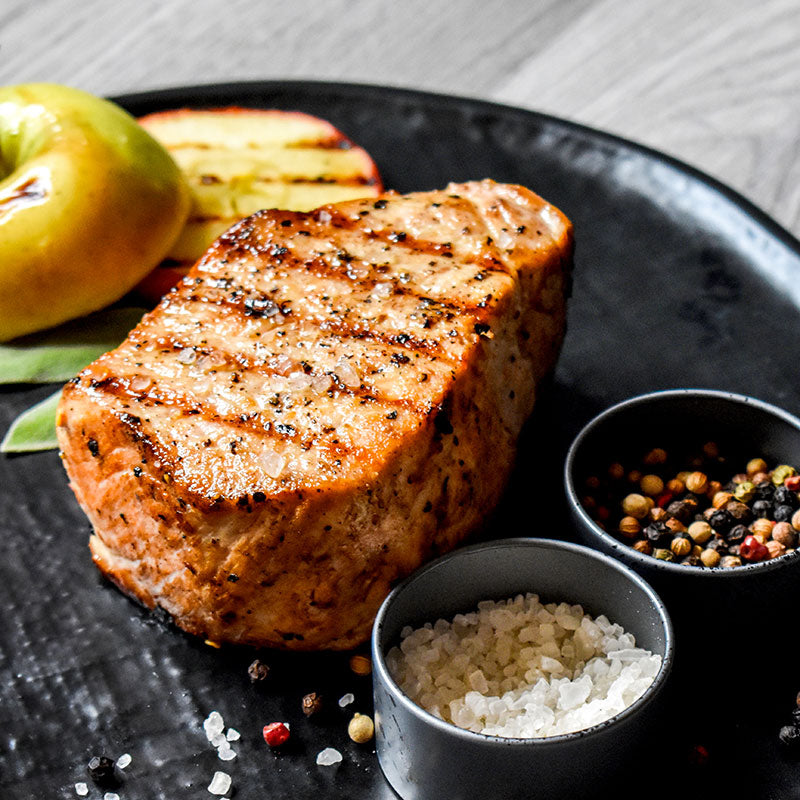 boneless pork chop on a black plate with salt and pepper