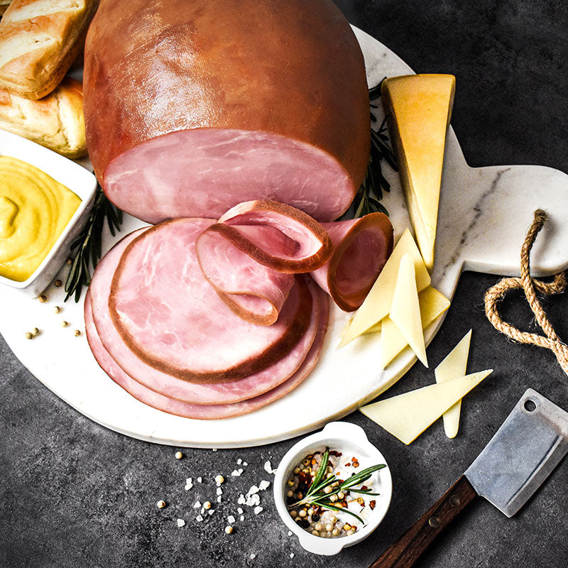 boneless smoked ham sliced on a white plate with garnishes placed around