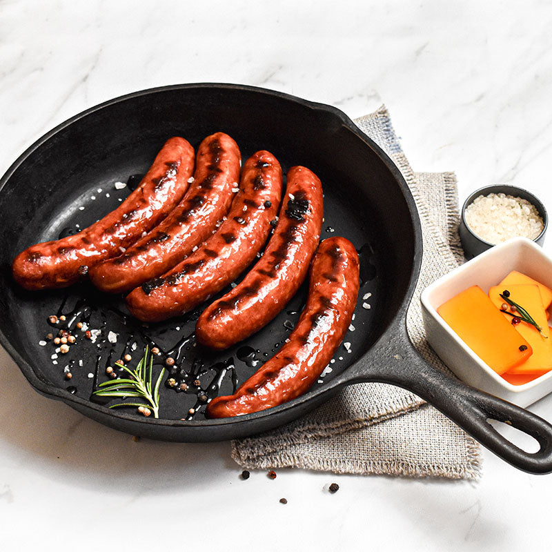 cheddar bratwurst in a skillet with cheese on the side