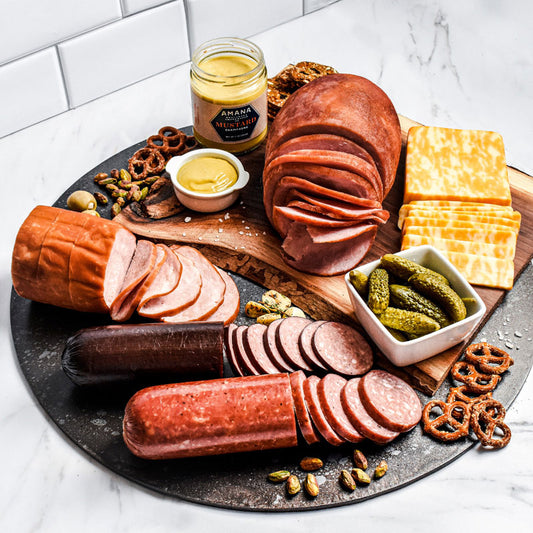 deli supreme items arranged on a black serving tray with pickles and pretzels