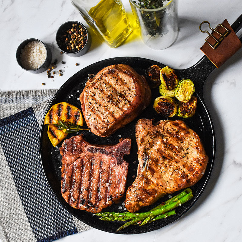 pork chop sampler items on a black serving plate with spices and olive oil on the side